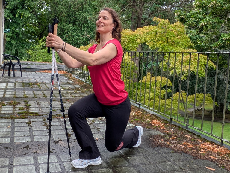Therapeutin führt Übung mithilfe von Nordic Walking Stöcken aus