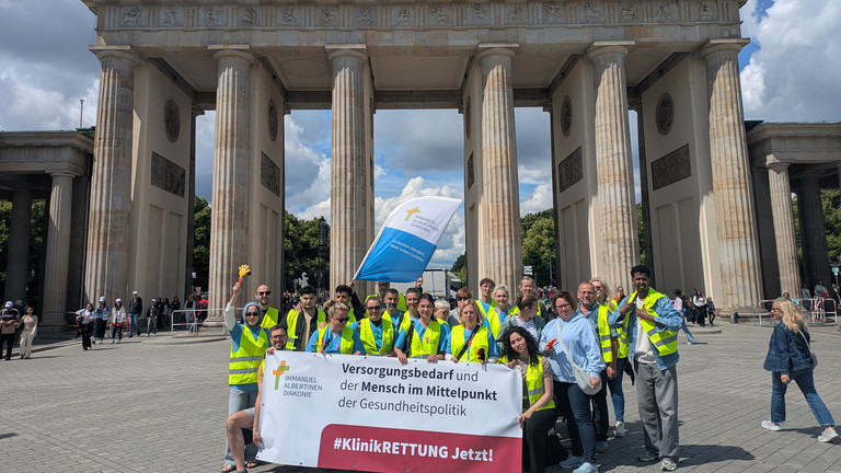 Mitarbeitende mit Banner vor Brandenburger Tor