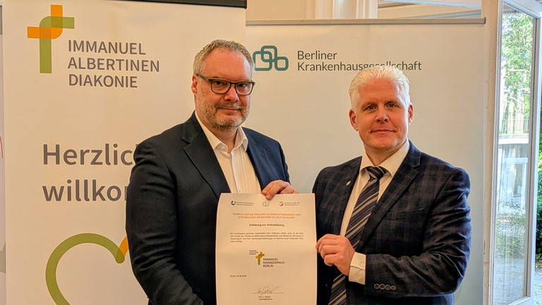 Roy J. Noack, Geschäftsführer des Immanuel Krankenhaus Berlin und Marc Schreiner, Geschäftsführer der Berliner Krankenhausgesellschaft halten die unterschriebene BKG-Charta Urkunde ins Bild Roy J. Noack, Geschäftsführer des Immanuel Krankenhaus Berlin und Marc Schreiner, Geschäftsführer der Berliner Krankenhausgesellschaft halten die unterschriebene BKG-Charta Urkunde ins Bild