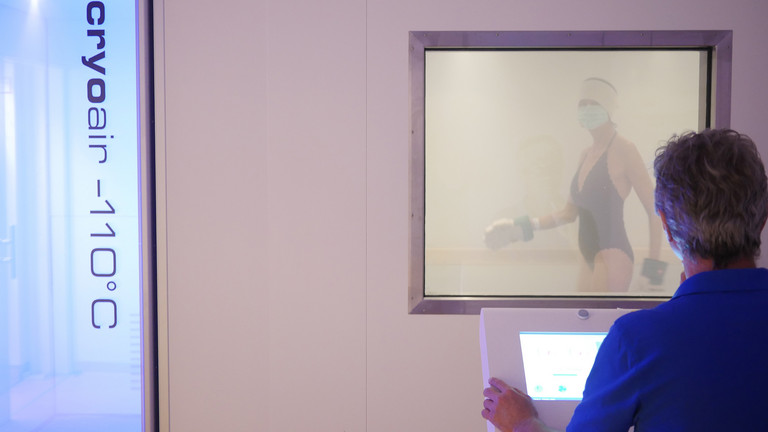 Patientin in Bewegung in der Kältekammer unter Aufsicht einer Fachkraft