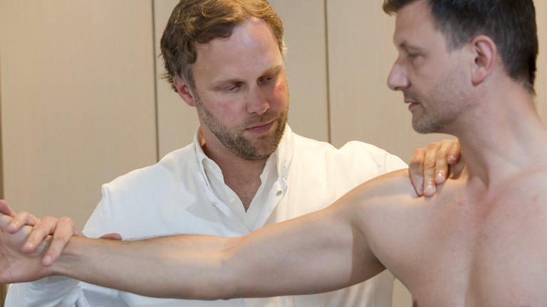 Arzt untersucht Schulter bei ausgestrecktem Arm - Immanuel Krankenhaus Berlin - Obere Extremität, Hand- und Mikrochirurgie - Krankheitsbilder - Schulter