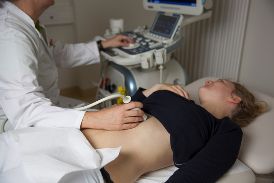 Auf Foto macht ein Arzt eine Ultraschall-Untersuchung bei einer Patientin Auf Foto macht ein Arzt eine Ultraschall-Untersuchung bei einer Patientin