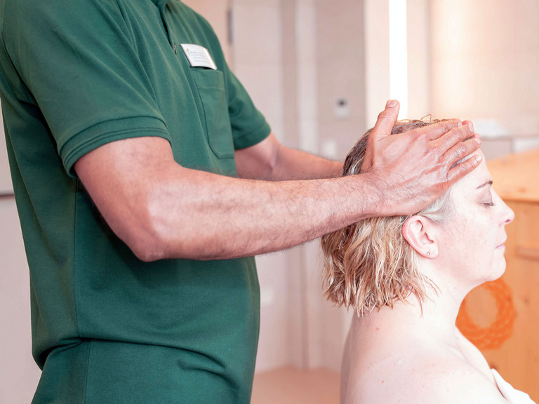 Therapeut massiert Kopf von Patientin mit Öl - Immanuel Ayurveda Zentrum