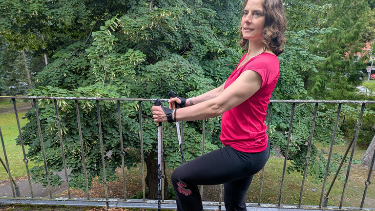 Therapeutin bei einer Nordic Walking Übung mit Stöckern auf einer Terrasse