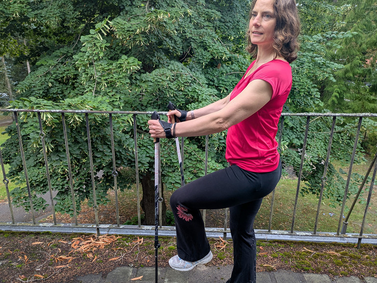 Therapeutin bei einer Nordic Walking Übung mit Stöckern uaf einer Terrasse