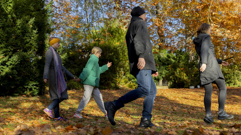 Eine Familie mit zwei Kindern beim Spaziergang durch den herbstlich belaubten Wald 
