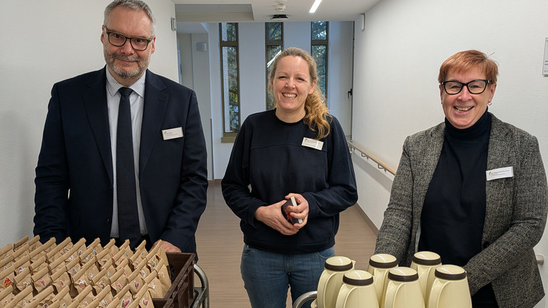 Geschäftsführer Roy J. Noack, Klinikseelsorgerin Marion Wunderlich und Pflegedirektorin Martina Kringe im Flur mit den Geschenken